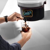 A person’s hands pouring cold brew from a Grady’s Cold Brew dispenser into a glass filled with ice.