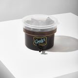 A Grady’s Cold Brew dispenser partially filled with cold brew and visible bean bags steeping inside, sealed with a clear plastic lid.