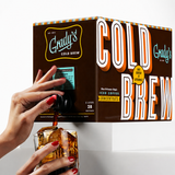 Hand dispensing Grady's Cold Brew New Orleans-Style Iced Coffee Concentrate from a 5-liter bag-in-box container into a glass filled with ice.